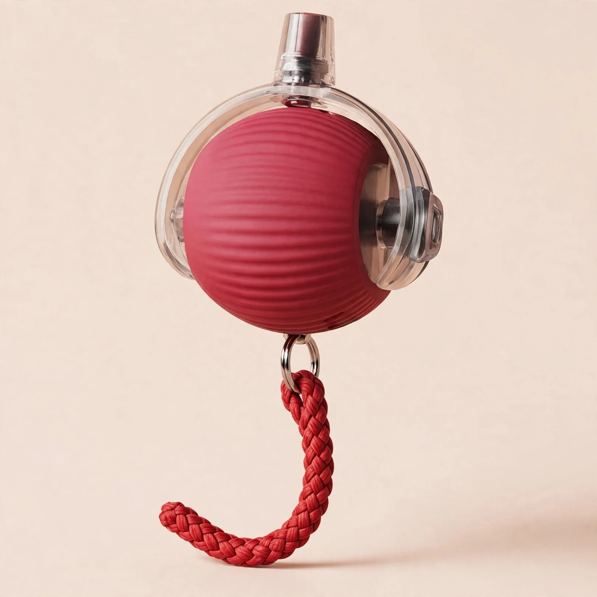 Red rope-textured smart rolling cat ball with a transparent outer shell, metal USB charging port on top, and a braided red rope tail hanging below, on a beige background.