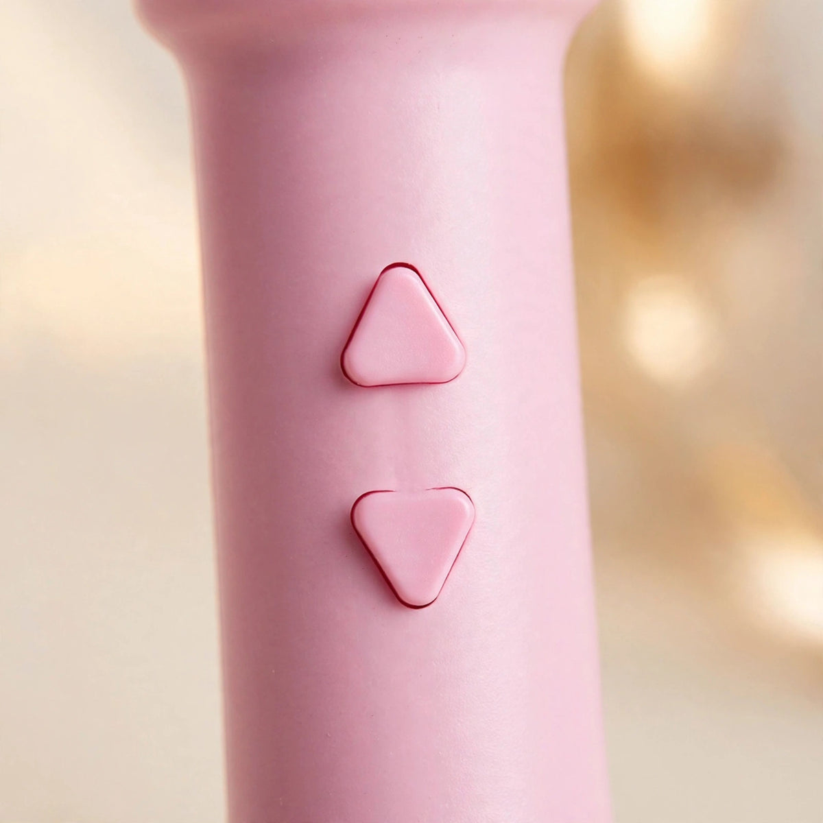 Close-up of the pink teaser wand handle showing its two triangular control buttons: up for one-click eject and down for slow auto-retract.
