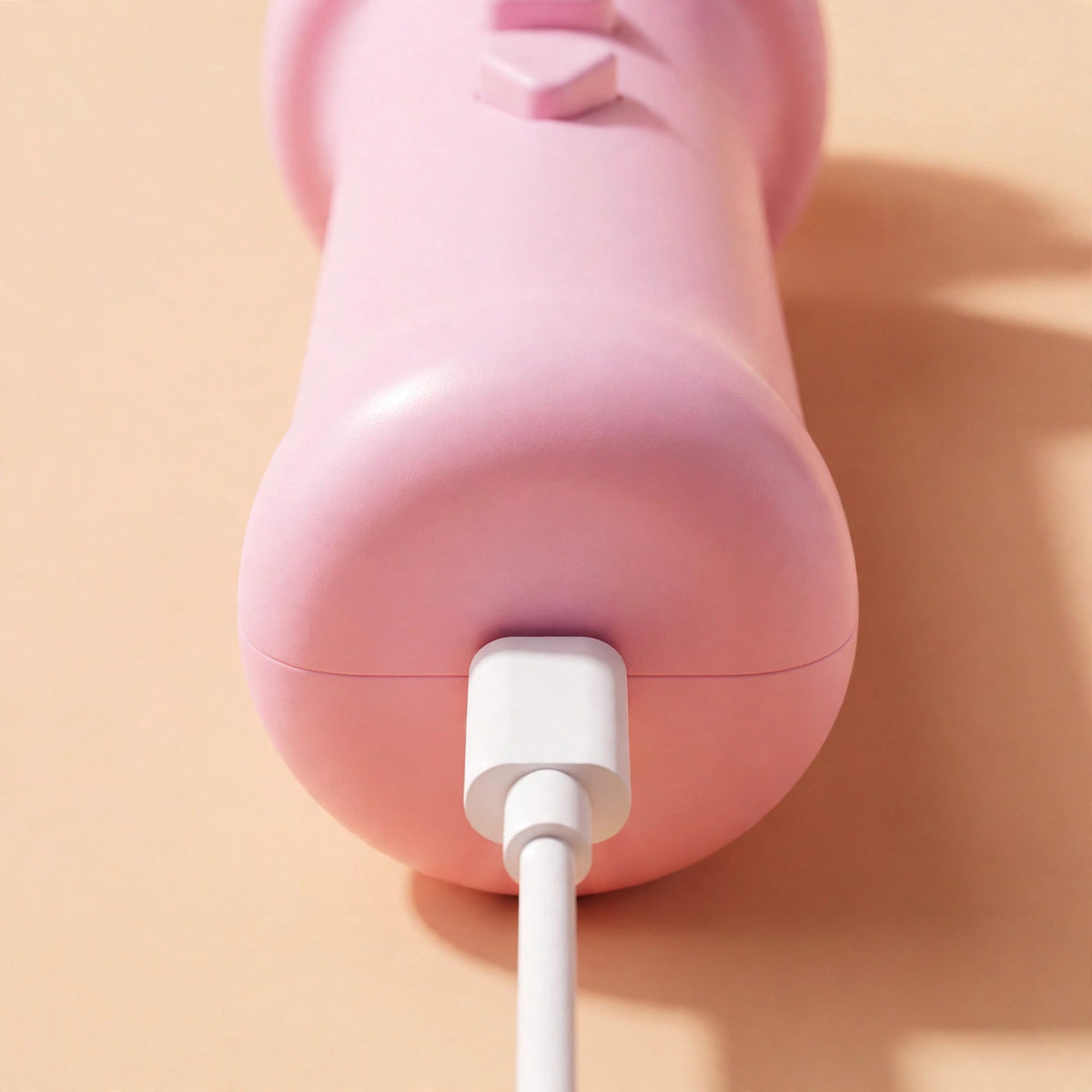 Close-up of the cherry-pink teaser wand's handle base with a white USB-C cable plugged into its Type-C charging port.